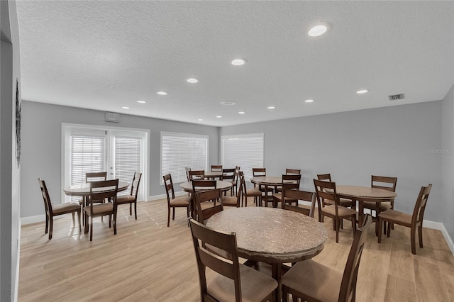 dining space featuring light hardwood / wood-style flooring and a textured ceiling