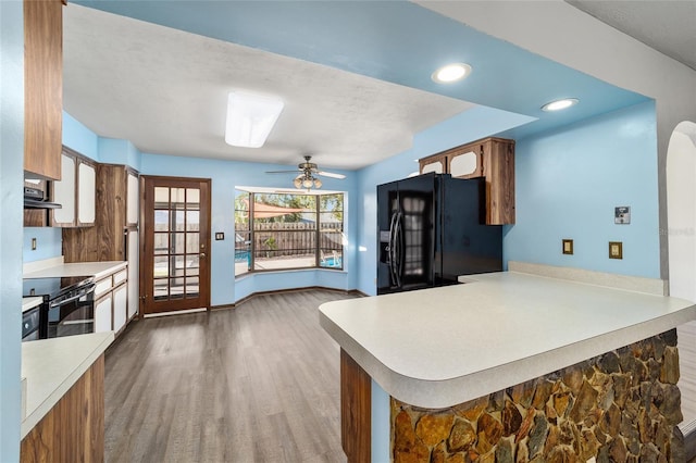 kitchen featuring ceiling fan, wood-type flooring, black appliances, ventilation hood, and kitchen peninsula