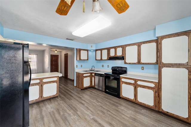kitchen with sink, light hardwood / wood-style flooring, ceiling fan, black appliances, and a barn door