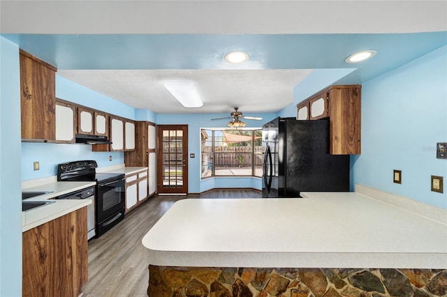 kitchen featuring black appliances, sink, hardwood / wood-style flooring, ceiling fan, and kitchen peninsula