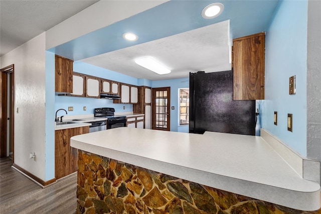 kitchen featuring sink, dark wood-type flooring, black appliances, and kitchen peninsula