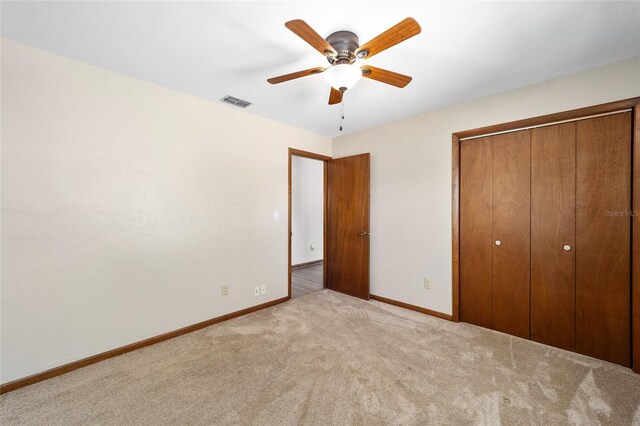 unfurnished bedroom featuring light carpet, a closet, and ceiling fan