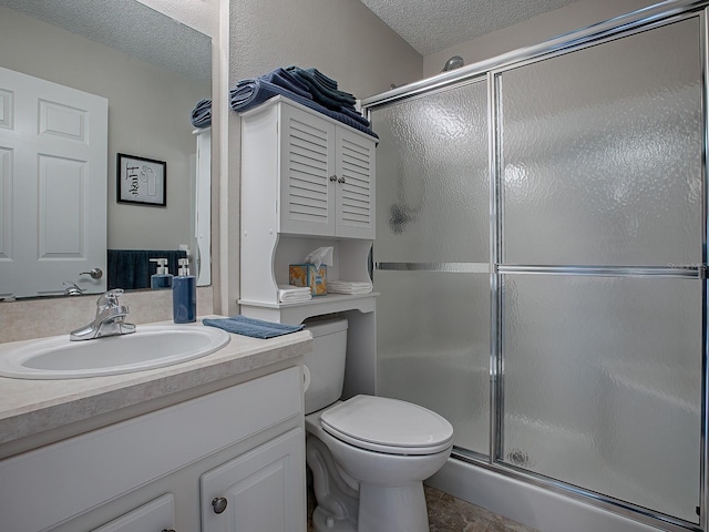 bathroom featuring a shower with door, vanity, a textured ceiling, and toilet