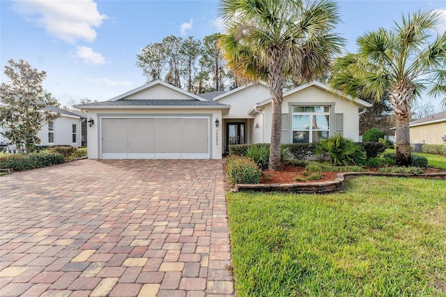 ranch-style home with an attached garage, a front lawn, decorative driveway, and stucco siding