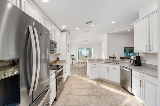 kitchen featuring appliances with stainless steel finishes, white cabinetry, sink, kitchen peninsula, and light tile patterned flooring