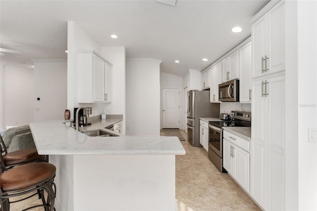 kitchen with white cabinetry, a kitchen bar, kitchen peninsula, stainless steel appliances, and sink