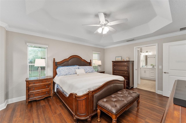 bedroom featuring ensuite bath, dark hardwood / wood-style flooring, ornamental molding, ceiling fan, and a tray ceiling