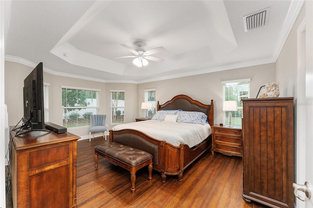 bedroom with dark wood-type flooring, ceiling fan, a tray ceiling, and multiple windows