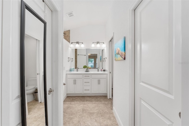 bathroom featuring toilet, vanity, and vaulted ceiling