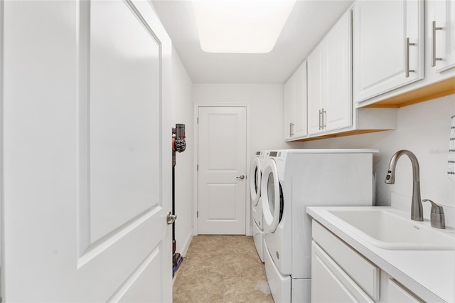 clothes washing area with cabinets, washing machine and clothes dryer, and sink