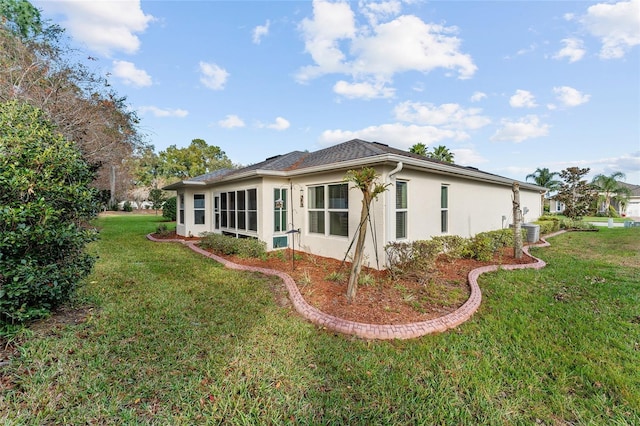 back of property with central AC and a lawn