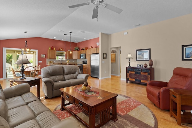 living room featuring light hardwood / wood-style flooring, ceiling fan with notable chandelier, and vaulted ceiling