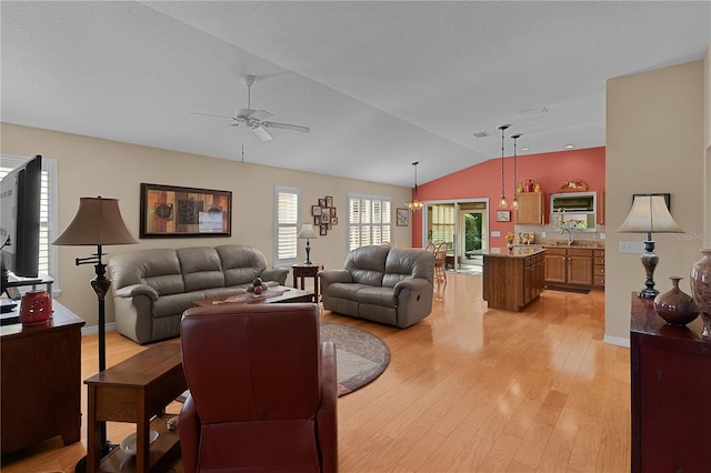 living room featuring ceiling fan, sink, light hardwood / wood-style floors, and lofted ceiling