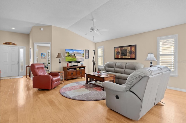 living room with ceiling fan, light hardwood / wood-style floors, a wealth of natural light, and vaulted ceiling