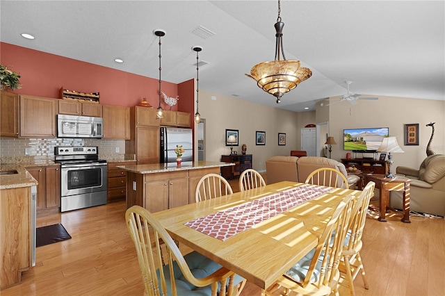 dining area with ceiling fan, lofted ceiling, and light wood-type flooring