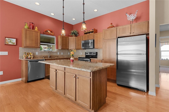 kitchen with light hardwood / wood-style floors, tasteful backsplash, decorative light fixtures, a kitchen island, and stainless steel appliances