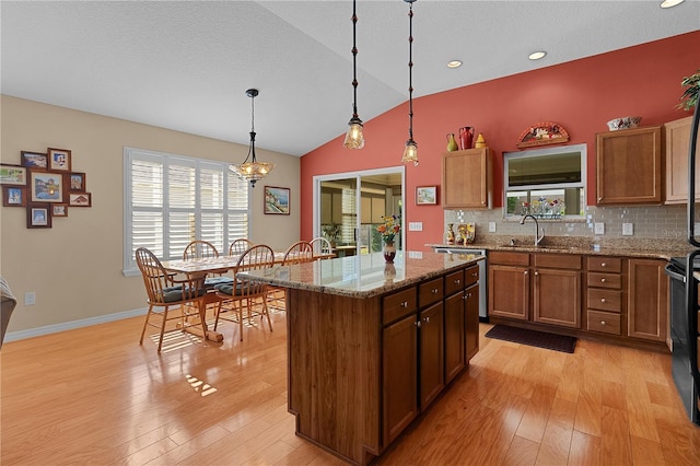 kitchen featuring light stone countertops, tasteful backsplash, vaulted ceiling, decorative light fixtures, and a kitchen island