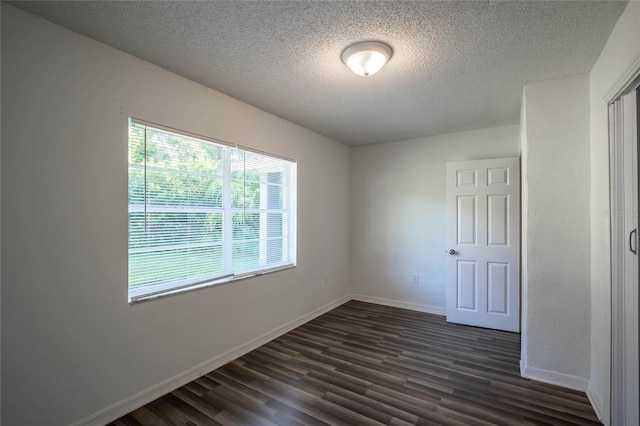 unfurnished room featuring dark hardwood / wood-style flooring and a textured ceiling