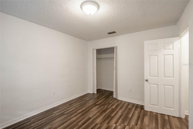 unfurnished bedroom featuring dark hardwood / wood-style flooring, a textured ceiling, and a closet