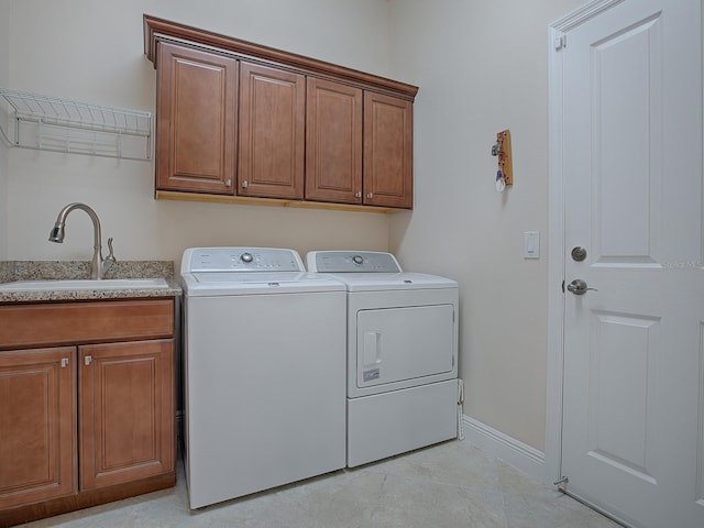 laundry area with washing machine and dryer, cabinet space, a sink, and baseboards