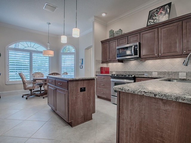 kitchen featuring hanging light fixtures, backsplash, appliances with stainless steel finishes, a kitchen island, and ornamental molding