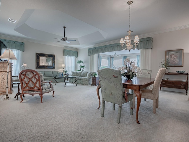 carpeted dining space featuring a healthy amount of sunlight, crown molding, visible vents, and a tray ceiling