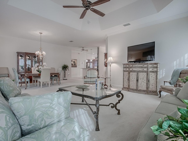 carpeted living room with a raised ceiling, crown molding, and ceiling fan with notable chandelier