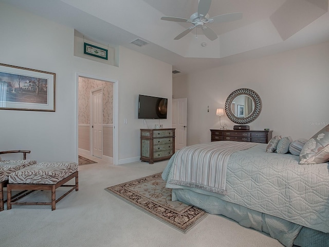 carpeted bedroom featuring a raised ceiling, ceiling fan, and ensuite bathroom