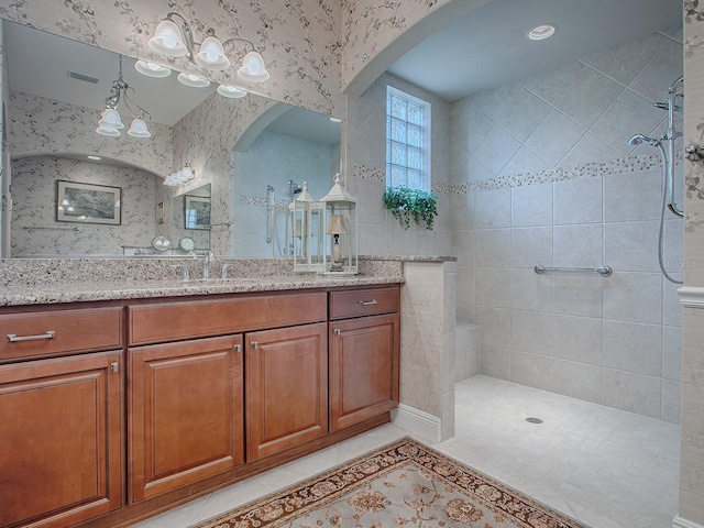 bathroom featuring tile patterned floors, vanity, a chandelier, and tiled shower