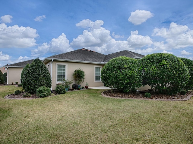 back of property with a yard and stucco siding