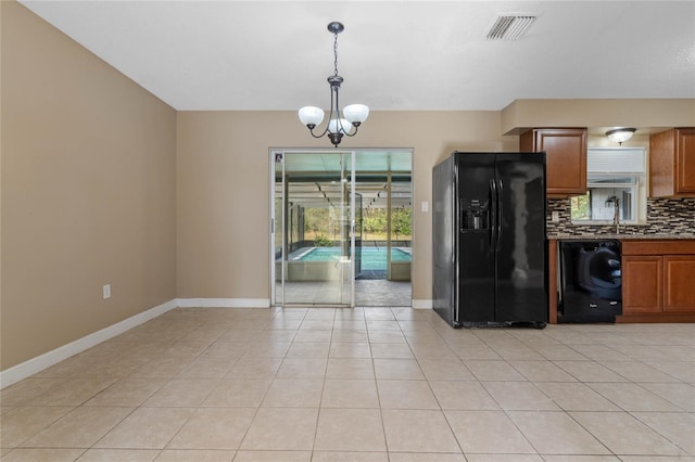 kitchen featuring black fridge, pendant lighting, a chandelier, washer / dryer, and decorative backsplash