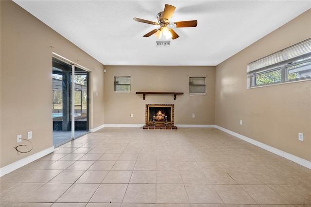 unfurnished living room featuring a fireplace, ceiling fan, and light tile patterned flooring