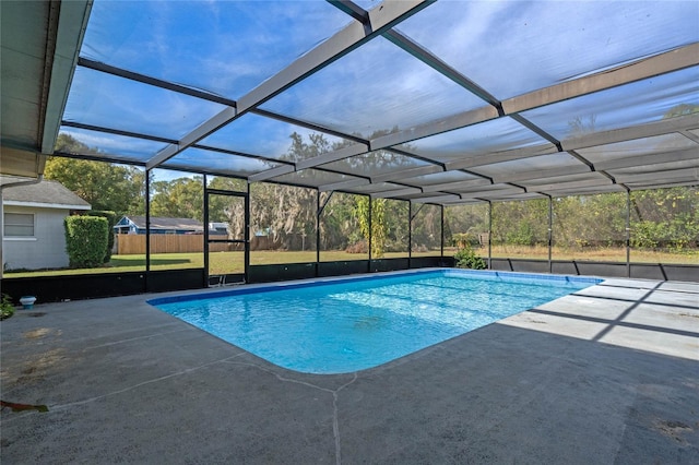 view of pool with glass enclosure, a patio area, and a yard