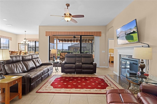 tiled living room featuring ceiling fan with notable chandelier and a fireplace