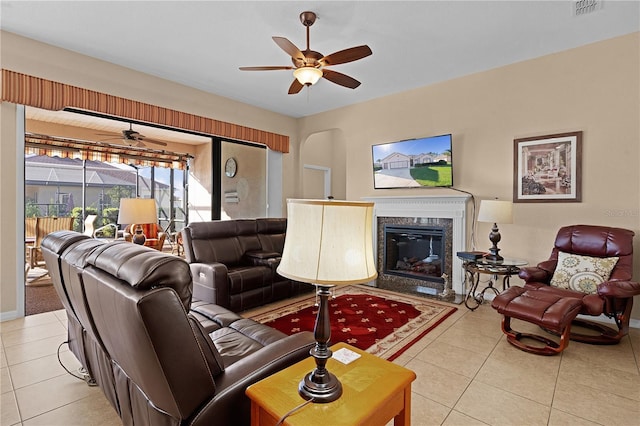 tiled living room with ceiling fan and a fireplace