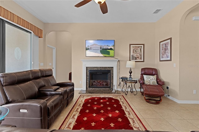 living room featuring ceiling fan, a fireplace, and light tile patterned flooring