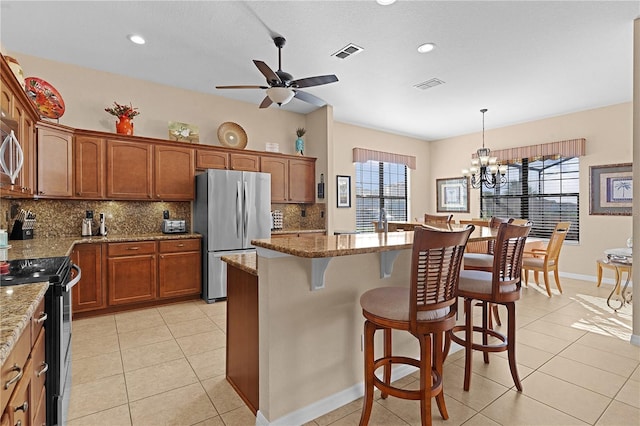 kitchen with light stone countertops, hanging light fixtures, stainless steel appliances, tasteful backsplash, and plenty of natural light