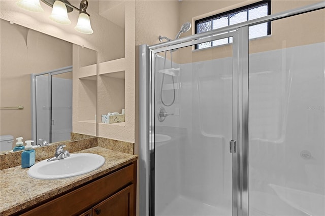 bathroom with vanity, a shower with shower door, and toilet