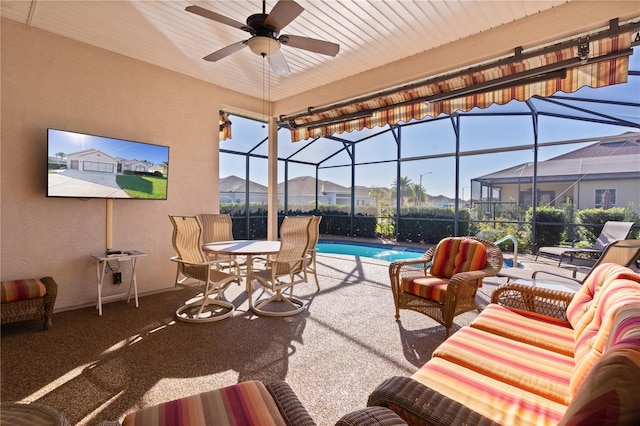 view of patio with outdoor lounge area, glass enclosure, and ceiling fan