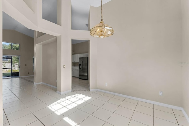 tiled spare room with high vaulted ceiling and an inviting chandelier