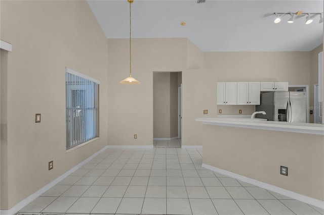 kitchen with sink, light tile patterned floors, stainless steel refrigerator with ice dispenser, decorative light fixtures, and white cabinets