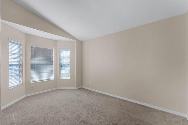 carpeted spare room featuring vaulted ceiling