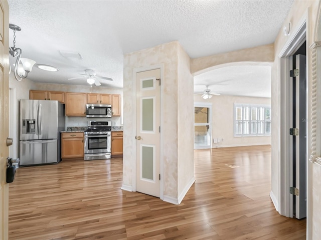 kitchen with ceiling fan, light hardwood / wood-style floors, hanging light fixtures, and appliances with stainless steel finishes