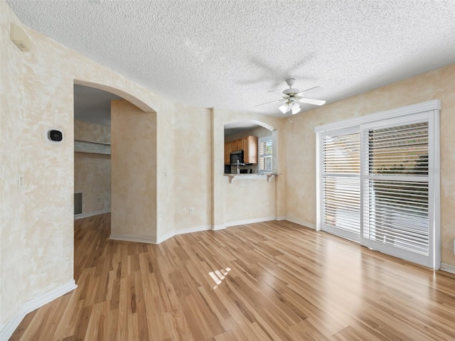 unfurnished living room with a textured ceiling, light wood-type flooring, and ceiling fan