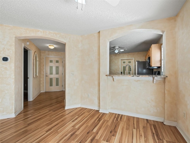 spare room with a textured ceiling, light hardwood / wood-style floors, ceiling fan, and sink