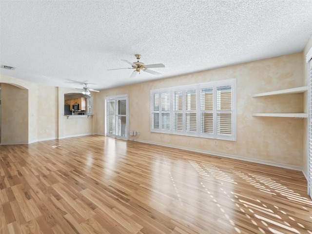 unfurnished living room featuring a textured ceiling, light hardwood / wood-style floors, and ceiling fan