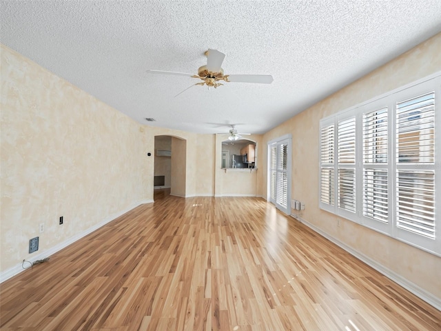 unfurnished living room with ceiling fan, light hardwood / wood-style floors, and a textured ceiling