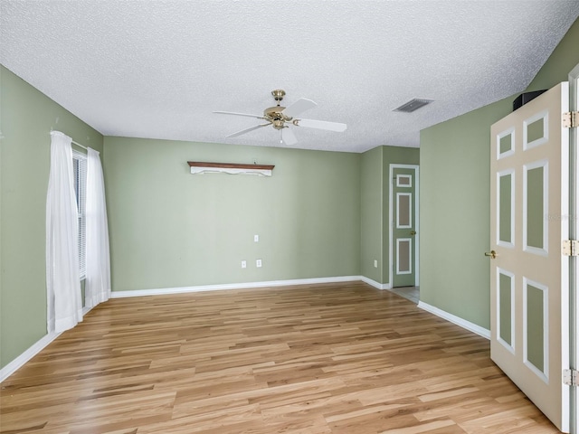 empty room with a textured ceiling, light wood-type flooring, and ceiling fan