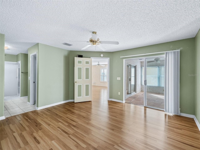 unfurnished room with a textured ceiling, light wood-type flooring, and ceiling fan