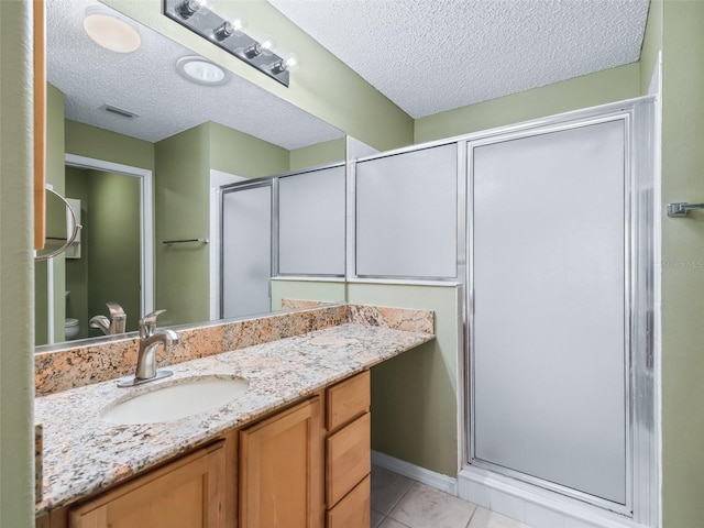 bathroom featuring vanity, tile patterned floors, toilet, a textured ceiling, and walk in shower